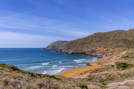 Unberührter Strand an der Costa Cálida in Murcia mit Holzsteg über Dünen und klarem Mittelmeerwasser